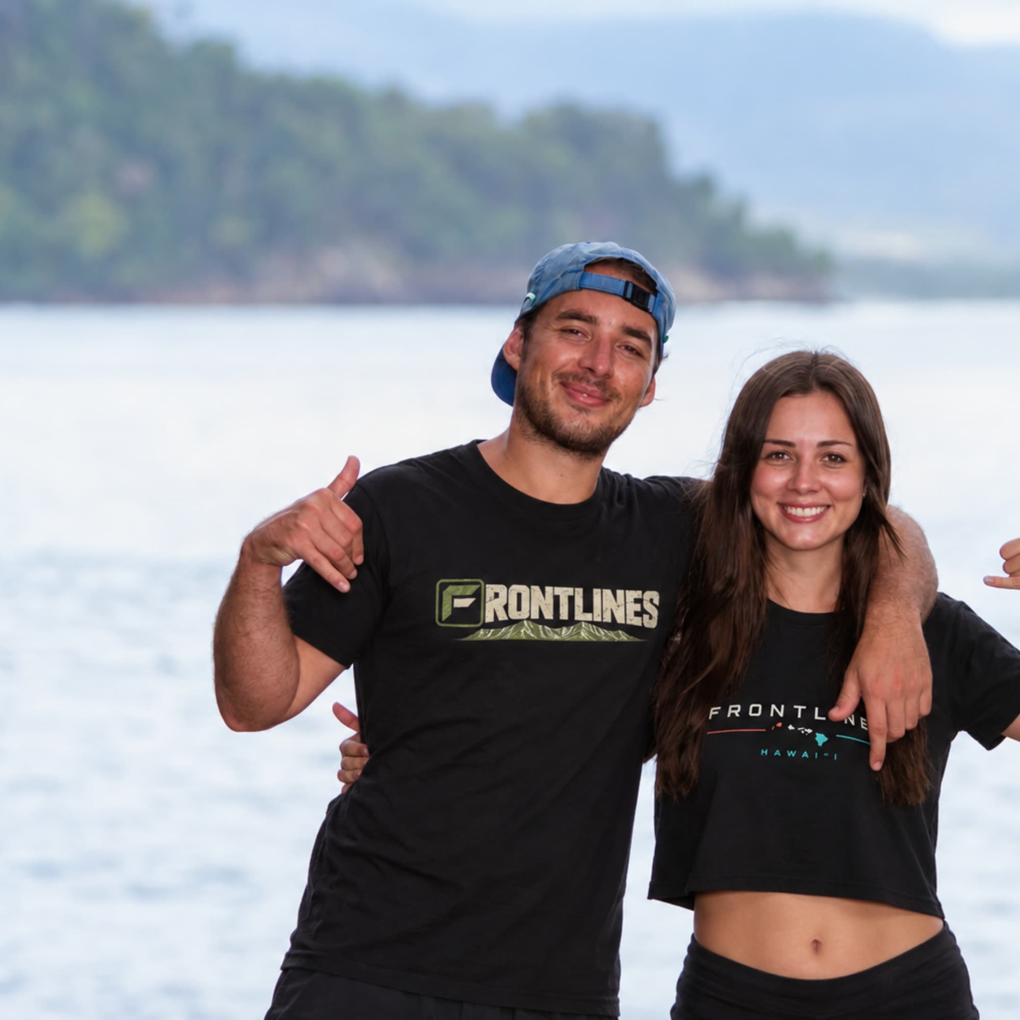 Two people wearing Frontlines lifestyle tees beside the ocean