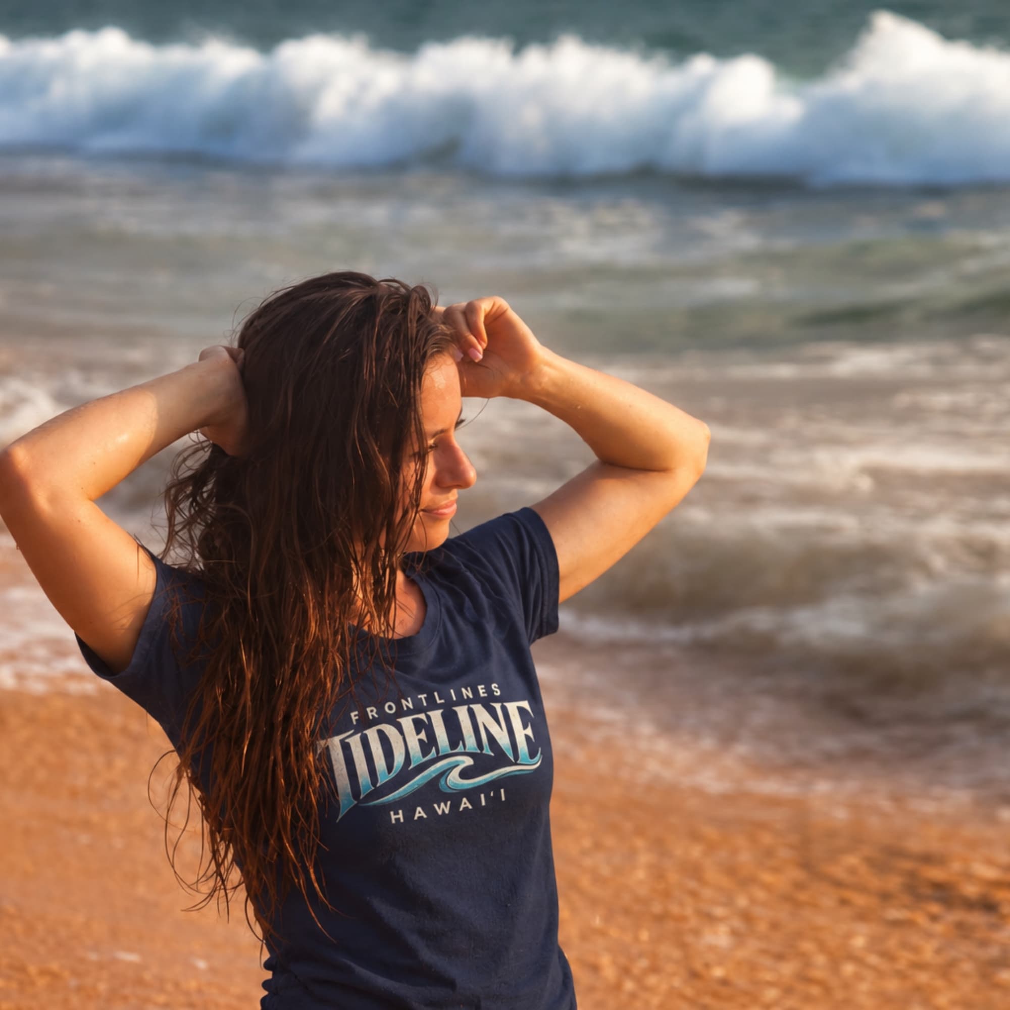 A woman wearing a navy Frontlines Tideline tee at the shoreline