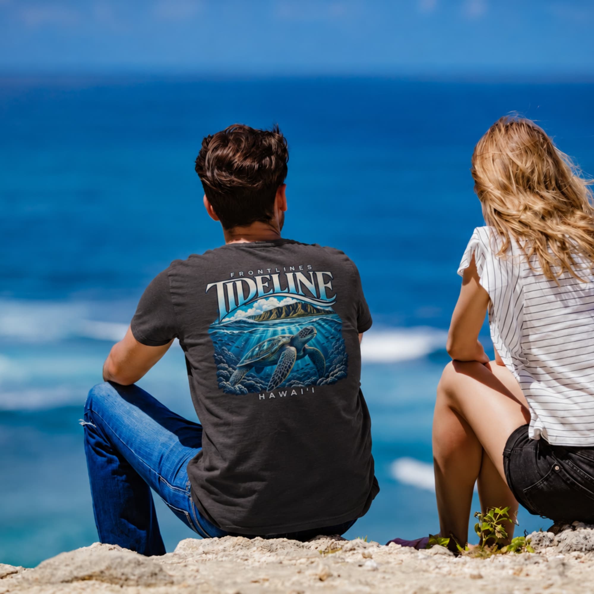 Two people overlooking the ocean, with a Frontlines Tideline sea turtle graphic on the man's tee